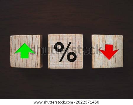 Business, Interest rate financial and mortgage rates concept. Close up percentage symbol with red decrease and green increase arrow icon symbolizing on wooden cube block on dark wooden background.