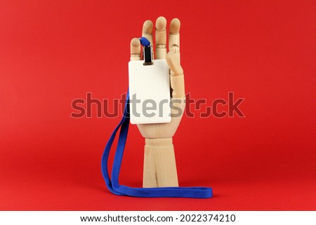 White badge with blue lace in wooden hand on red background