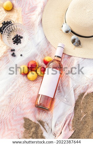 Summer beach picnic on the coast. Bottle of rose wine, fruits, summer accessories. Romantic party concept. Top view - Image