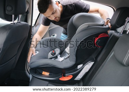 Man installs a child car seat in car at the back seat. Responsible father thought about the safety of his child Royalty-Free Stock Photo #2022389279