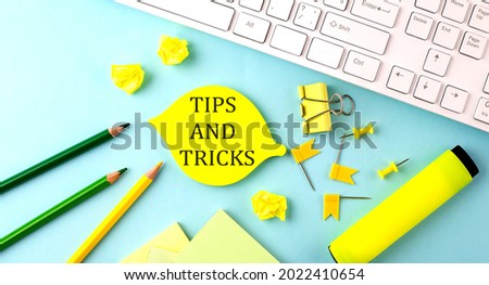 Text sign showing TIPS AND TRICKS with office tools and keyboard on blue background