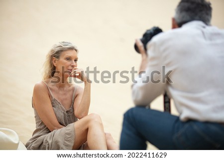 photographer capturing mature woman on a sand dune Royalty-Free Stock Photo #2022411629