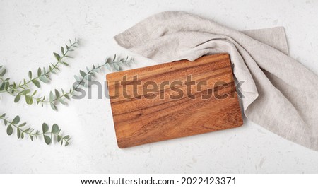 Wood cutting board with napkin on marble table, top view Royalty-Free Stock Photo #2022423371