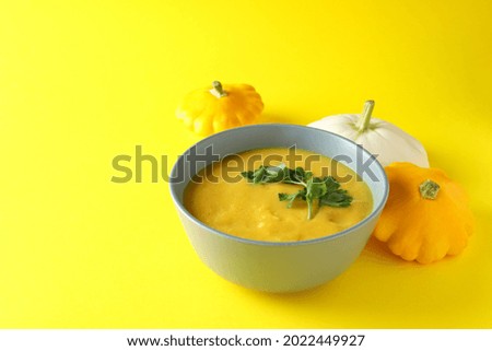 Concept of tasty food with pumpkin soup on yellow background