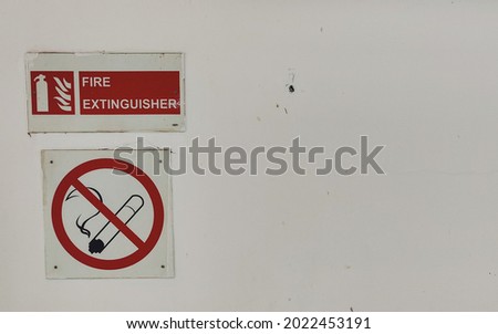a fire extinguisher and no smoking sign on a white wall