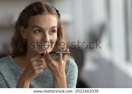 Happy gen Z girl recording audio message on smartphone. Millennial making phone call on speaker, giving command to virtual assistant, using voice recognition app, chatting on smartphone messenger Royalty-Free Stock Photo #2022462038