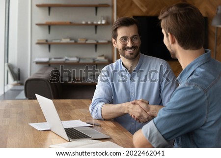 Two happy confident businessmen shaking hands at workplace. Business leader, employer hiring and welcoming candidate after job interview. Customer and broker finishing up meeting, expressing respect Royalty-Free Stock Photo #2022462041