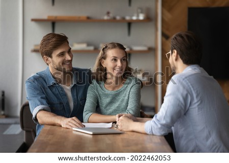 Happy young married family couple consulting realtor, agent, advisor, consultant, talking on meeting, discussing real estate property buying, mortgage, house rent, smiling, laughing Royalty-Free Stock Photo #2022462053