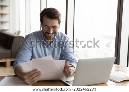 Happy business professional in glasses reviewing official legal documents, reading received paper letter with good news, bank notice, approved loan agreement. Paperwork, correspondence concept Royalty-Free Stock Photo #2022462293