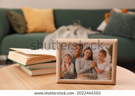 Framed family photo and books on wooden table indoors Royalty-Free Stock Photo #2022466502