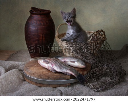 Still life with fish and little kitten