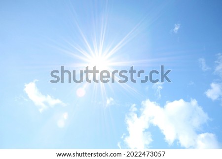 Blue sky with white fluffy clouds and sun reflection. Sunny background. Sun appear directly above Thailand. The afternoon summer sun shines on a beautiful sky with clouds. Hot weather, summer season. Royalty-Free Stock Photo #2022473057
