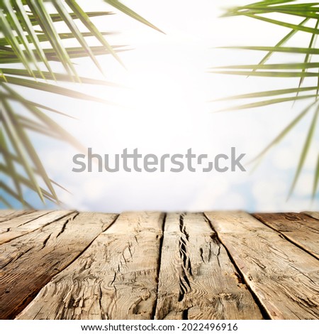 The sun, exotic palm trees and a wooden table on a beautiful hot summer day 
