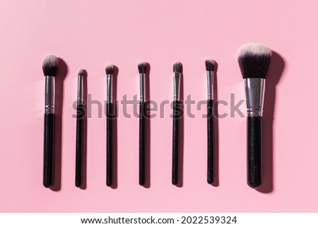 Various make-up brushes on pink background, top view. Cosmetics and beauty concept.