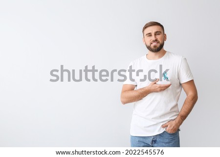 Man with blue ribbon on light background. Prostate cancer awareness concept Royalty-Free Stock Photo #2022545576
