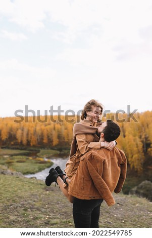 A happy couple in love in casual clothes travel together, hike and have fun in the fall forest on a weekend in nature in autumn outdoors, selective focus