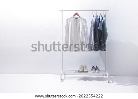 Mens in different colors with polo shirt, striped shirt hanging on hanger with two pair shoes 

