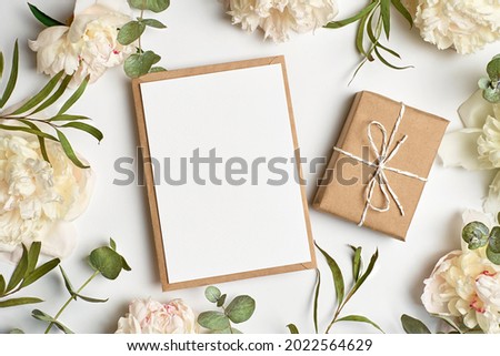 Invitation or greeting card mockup with envelope, gift box and white peony flowers and eucalyptus twigs Royalty-Free Stock Photo #2022564629