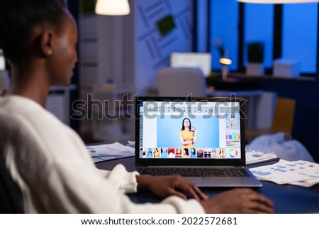 Creative african american retoucher working at design production retouching photography using editing software technology. Photographer on laptop. Woman overworking in creativity office at night