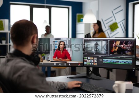 Video editor in web online production conference with project manager on video call editing client work, getting feedback on company movie using post production software on two monitors