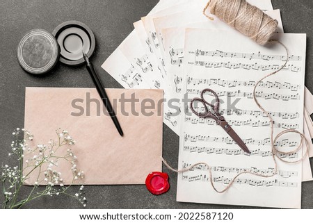 Composition with nib pen, ink and musical note sheets on black table