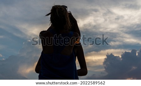 Silhouette of two female persons in the foreground with a beautiful cloudy sunset in the background.