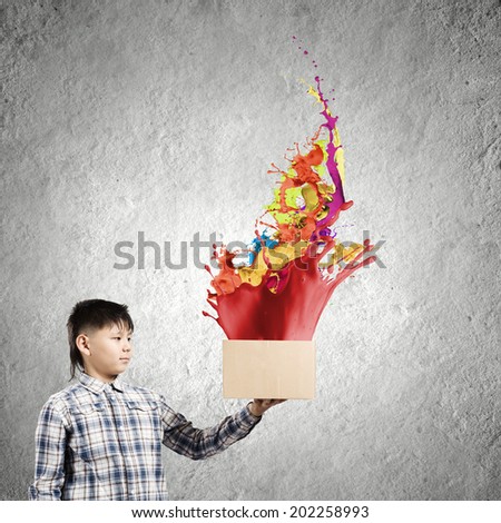 Cute boy splashing colorful paint from carton box