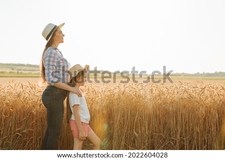 side view, portrait family of farmers mother with daughter in hats in wheat golden field. Agro walk in the countryside Royalty-Free Stock Photo #2022604028