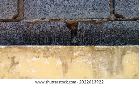 Yellow faded wall and concrete brick wall as background.