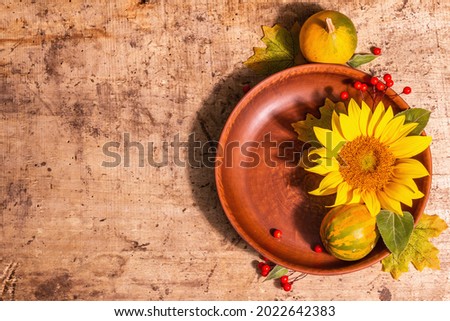 Autumn composition. Table setting, sunflower, red berries, and pumpkins. Festive good mood background, top view