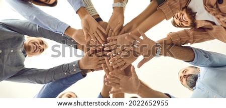Bottom view of a variety of happy men and women folding their arms together as a symbol of cooperation. People who stand in a circle and demonstrate unity and teamwork. Human support concept. Royalty-Free Stock Photo #2022652955