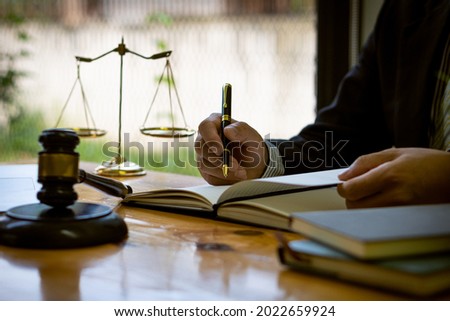 Male lawyer working at a desk in the office Highlight the scales of justice and the hammer of the judges with laptops and notebooks placed in front of them.