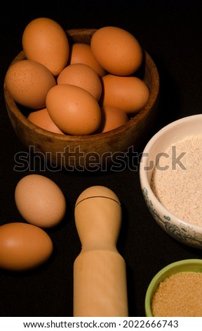 flour, eggs, sugar, rolling pin. ingredients for cooking bread. food on black background to make homemade bread