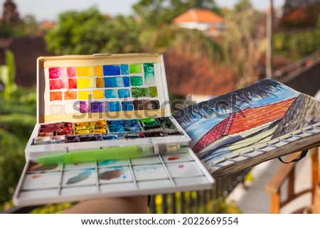 A box of watercolour paints. sketchbook outdoors.