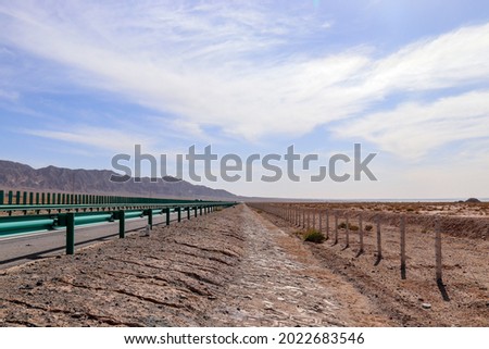long highway on gobi desert, road has been sand blowing with wilderness background in Qingha.China