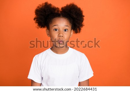 Photo of small cute girl blow kiss wear white t-shirt isolated on orange color background