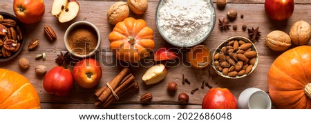 Autumn fall baking background with pumpkins, apples, nuts, food ingredients and seasonal spices, banner. Cooking pumpkin or apple pie and cookies for Thanksgiving and autumn holidays. Royalty-Free Stock Photo #2022686048
