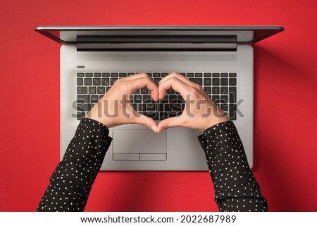 Overhead photo of grey laptop and hands with gesture as heart isolated on the red backdrop Royalty-Free Stock Photo #2022687989