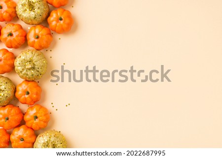 Top view photo of halloween stylish decorations orange golden small pumpkins and golden sequins on isolated beige background with copyspace