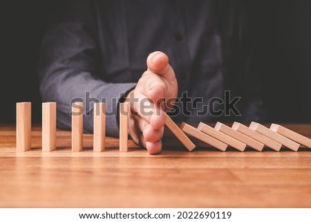 Closeup businessman stop the crash of domino effect on the table Royalty-Free Stock Photo #2022690119