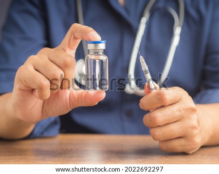 A doctor is holding a vaccine bottle and syringe. Vaccine for prevention and treatment from virus infection. Close-up photo. Concept of medical and the fight against the virus. Royalty-Free Stock Photo #2022692297