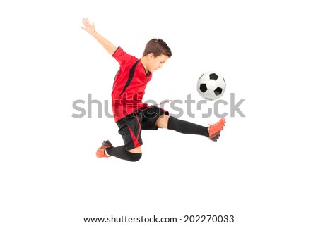Junior football player kicking a ball isolated on white background