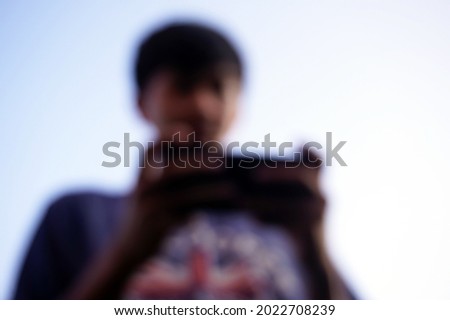Defocused of a boy playing game in the mobile phone.                               