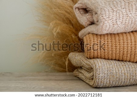 Bunch of knitted warm pastel color sweaters with different knitting patterns folded in stack, clearly visible texture. Stylish fall-winter season knitwear clothing. Close up, copy space for text. Royalty-Free Stock Photo #2022712181