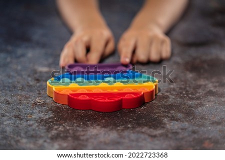 Little girl playing with rainbow colored pop it silicone toy antistress