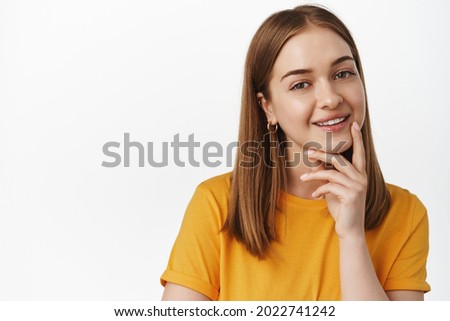 Close up portrait of smiling blond woman look intrigued, smiling thoughtful, interesting suggestion, standing pleased in yellow t-shirt against white background