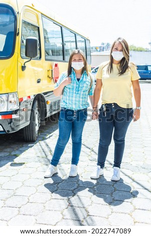Portrait of a mother and a girl next to the school bus