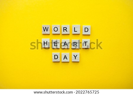 The inscription world heart day from wooden blocks on a bright yellow background