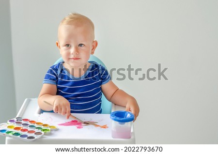 Happy cheerful child drawing with brush in album using a lot of painting tools. Creativity concept.