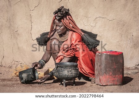 Portrait of a woman from the Himba tribe preparing food in a traditonal Himba village in Namibia, Africa. Himbas are an African tribe located in North Namibia and South Angola. Royalty-Free Stock Photo #2022798464